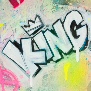 May include: Abstract graffiti art featuring the word "KING" in bold white letters with black outlines and a crown. The background has a mix of colors, including pink, yellow, and green, with paint splatters.
