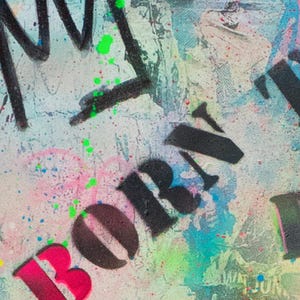 May include: Abstract artwork with a textured background featuring graffiti-style lettering and paint splatters. The word "BORN" is prominently displayed in a bold, stylized font, with vibrant pink and black colors. Splashes of green, blue, and pink add to the artwork's dynamic feel.