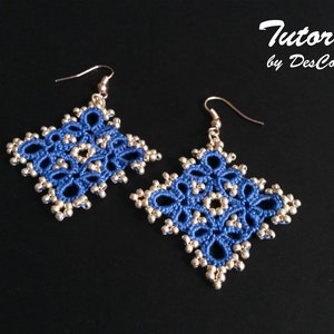 Puede incluir: Un par de pendientes azules y plateados con un diseño delicado e intrincado. Los pendientes son de forma cuadrada y presentan un patrón floral.
