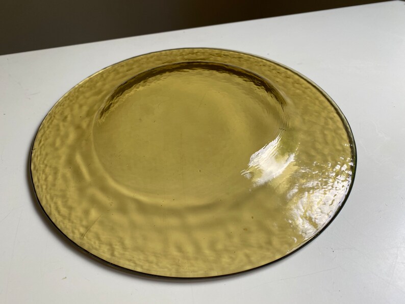 May include: A large, round, amber-colored glass plate with a textured surface.