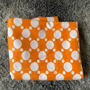 Peut inclure: Tissu orange à pois blancs.