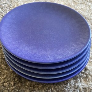 May include: A stack of five blue ceramic plates. The plates are a deep blue colour and have a slightly textured surface.
