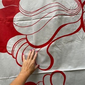May include: White fabric with a red abstract design. The design features a series of overlapping, curved shapes.