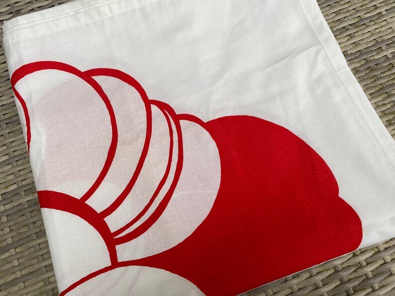 May include: White fabric with a red abstract design. The design is made up of overlapping circles and semi-circles.
