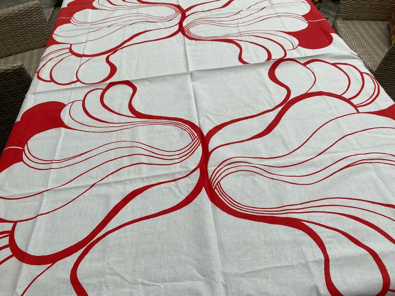 May include: White tablecloth with a red abstract design of swirling lines and shapes.