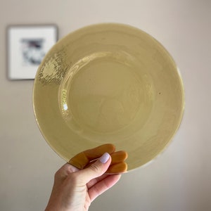 May include: A large, round, yellow glass charger plate.
