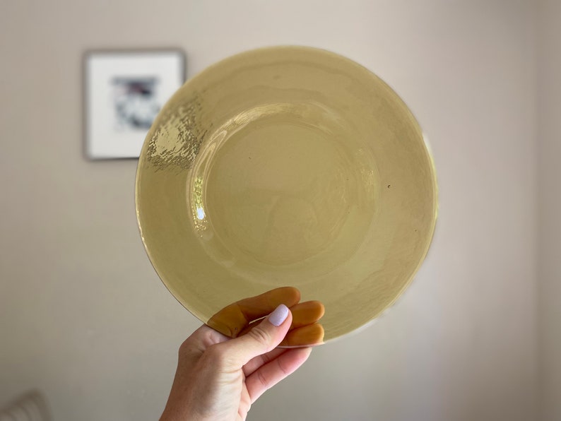 May include: A large, round, yellow glass charger plate.