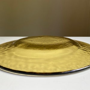 May include: A brown glass plate with a textured surface. The plate is round and has a slightly raised edge.