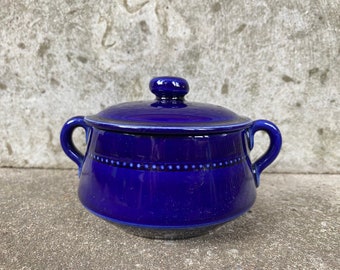 May include: A cobalt blue ceramic sugar bowl with a lid and two handles. The bowl has a white dotted line around the middle.