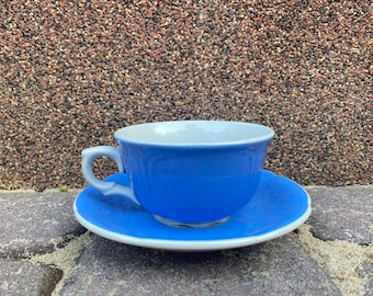 Peut inclure: Une tasse à thé et une soucoupe en bleu et blanc. La tasse a une forme arrondie et un intérieur blanc. La soucoupe est de la même couleur bleue avec un bord blanc.