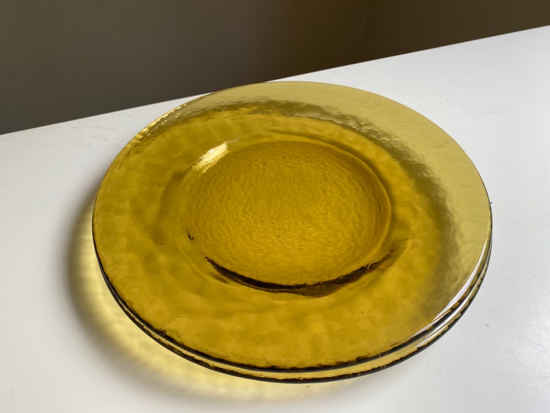 May include: A set of two amber glass dinner plates with a textured surface.