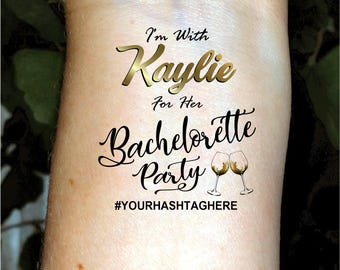Puede incluir: Un tatuaje temporal con el texto "I'm With Kaylie For Her Bachelorette Party #YOURHASHTAGHERE" y dos copas de vino doradas.