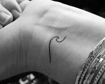May include: A simple black line wave tattoo on a person's wrist.