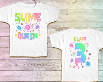 May include: Two white t-shirts with a slime theme. The front shirt says "Slime Queen" with colorful slime drips and stars. The back shirt says "Clair" with a number "3" and colorful slime drips.