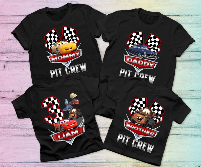 May include: Four black t-shirts with Cars characters and the text "Mommy Pit Crew", "Daddy Pit Crew", "Liam" and "Brother Pit Crew".