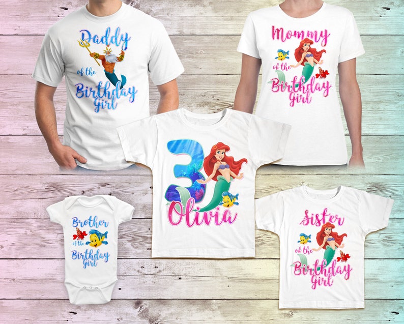 Puede incluir: Conjunto de cinco camisetas blancas con tem&aacute;tica de sirena. Las camisetas tienen diferentes textos e im&aacute;genes, incluyendo "Pap&aacute; de la ni&ntilde;a del cumplea&ntilde;os", "Mam&aacute; de la ni&ntilde;a del cumplea&ntilde;os", "Hermano de la ni&ntilde;a del cumplea&ntilde;os", "Hermana de la ni&ntilde;a del cumplea&ntilde;os" y una camiseta con el n&uacute;mero 3 y el nombre "Olivia".