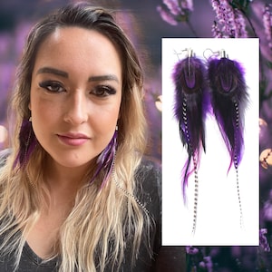 May include: Purple and black feather earrings with a silver chain. The earrings are long and dangle.