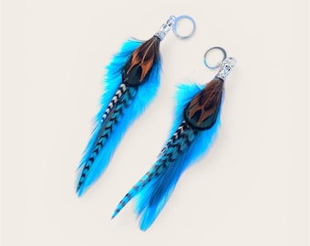May include: A pair of feather earrings with a silver-tone metal top and a circular hoop. The earrings feature a combination of blue, brown, and black feathers. The feathers are arranged to create a flowing, eye-catching design.