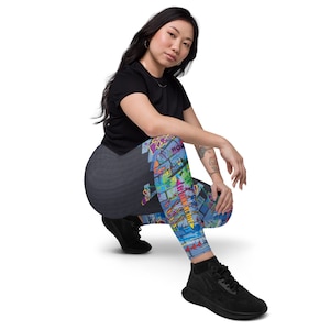 Puede incluir: Una mujer con una camiseta negra y leggings coloridos con un estampado de estilo graffiti. Los leggings muestran las palabras "ROW", "BANK", "NEW YORK" y "CITY".
