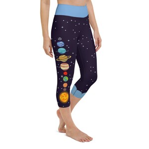 Puede incluir: Mallas capri azul oscuro con cintura y detalles en azul claro. Las mallas presentan una colorida ilustración del sistema solar, incluyendo el sol y los planetas, sobre un fondo estrellado. Una opción elegante y cómoda para yoga o uso diario.