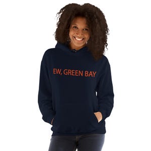 Peut inclure: Un sweat à capuche bleu marine foncé avec le texte "EW, GREEN BAY" imprimé en orange vif sur la poitrine. Le vêtement présente une poche kangourou à l'avant, des manches longues et une capuche avec des cordons de serrage bleu marine assortis.