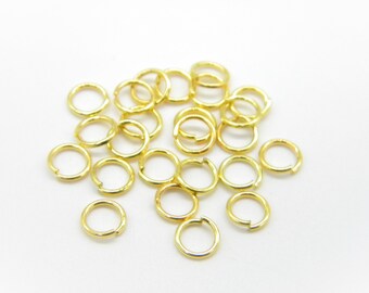 May include: A pile of gold jump rings, a type of jewelry finding used for connecting chains, cords, and other jewelry components.