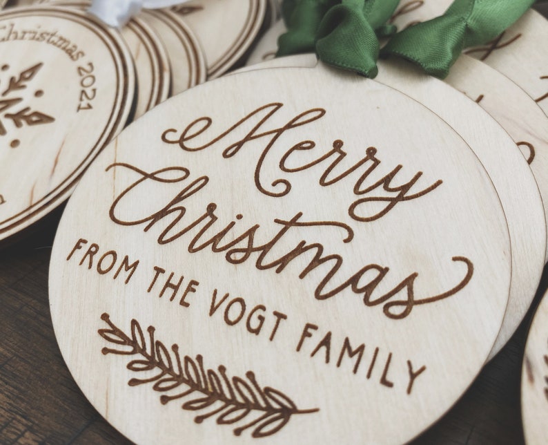 Puede incluir: Un conjunto de adornos redondos de madera con un mensaje grabado con l&aacute;ser que dice "Feliz Navidad de la familia Vogt". Los adornos est&aacute;n decorados con un sencillo dise&ntilde;o de hojas.