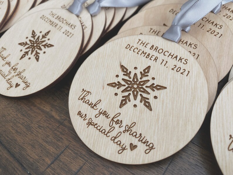 May include: Wooden round ornaments with a snowflake design and the text "Thank you for sharing our special day" and "The Brochaks December 11, 2021".