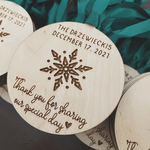 May include: Round wooden ornaments with a snowflake design and the text "The Drzewieckis December 17, 2021" and "Thank you for sharing our special day".
