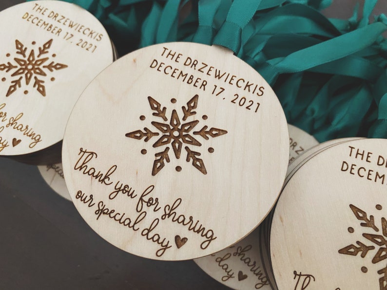 May include: Round wooden ornaments with a snowflake design and the text "The Drzewieckis December 17, 2021" and "Thank you for sharing our special day".