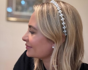May include: A pearl headband with a delicate design. The headband is made of small, round, white pearls. The pearls are arranged in a pattern along the band. The woman in the image is wearing a black top and has blonde hair.
