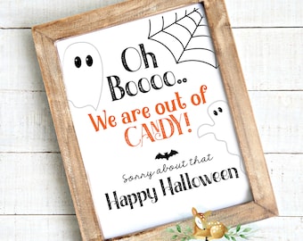 May include: A framed Halloween sign with a rustic wooden frame. The white sign features a black spiderweb, ghost illustrations, and the text "Oh Boooo... We are out of CANDY!" in black and orange. The sign also says "Sorry about that Happy Halloween."