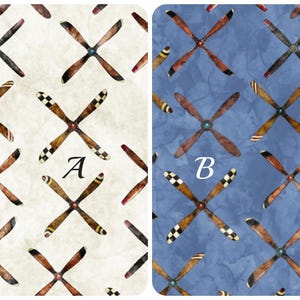 May include: Two fabric swatches with a repeating pattern of brown and white propeller designs. The swatch on the left is a cream color with the letter "A" in the center. The swatch on the right is a blue color with the letter "B" in the center.