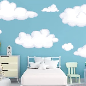 May include: A child's bedroom with a light blue wall decorated with white cloud decals. The room features a white bed, dresser, and chair. Decorative items include dolls and a small clock. A gray rug is on the floor.