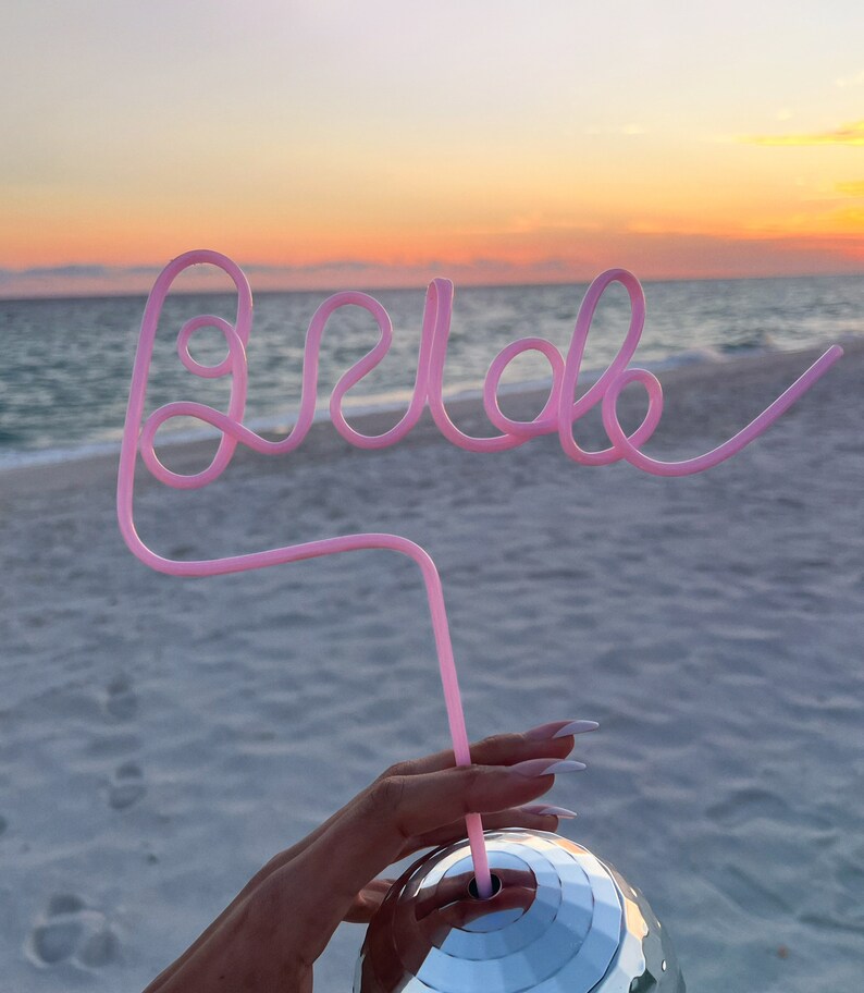 May include: Pink bendy straw shaped to spell "Hello" with a silver disco ball cup.