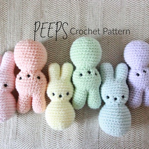 Puede incluir: Un conjunto de seis peluches de conejito Peep de crochet en colores pastel, incluyendo rosa, amarillo, verde y morado. Los peluches están dispuestos en una fila sobre una superficie marrón texturizada. El texto "PEEPS Crochet Pattern" es visible sobre los peluches.