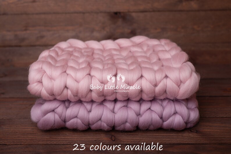 May include: Two chunky knit blankets in shades of pink and purple. The blankets are stacked on top of each other and have a woven texture. The text "Baby Little Miracle Photo Props" is printed on the top blanket.