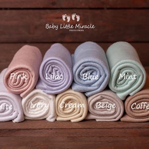 K&ouml;nnte beinhalten: Gerollte Baby-Foto-Requisiten in verschiedenen Farben wie Rosa, Lila, Blau und Mint, mit Etiketten f&uuml;r die Farben: Wei&szlig;, Elfenbein, Creme, Beige und Kaffee. Der Text "Baby Little Miracle PHOTO PROPS" ist ebenfalls vorhanden.