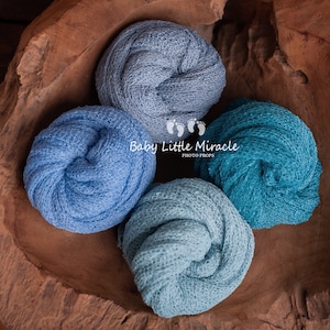Può includere: Quattro fasce per neonati arrotolate in tonalità di blu e verde acqua sono disposte in una ciotola di legno rustico. Le fasce sono realizzate in un tessuto a maglia strutturato. L'immagine include il testo "Baby Little Miracle PHOTO PROPS".