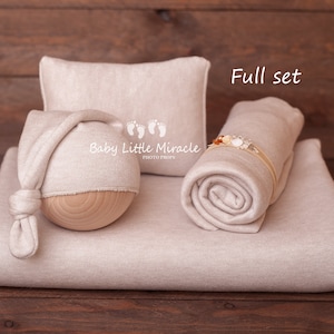 K&ouml;nnte beinhalten: Ein beiges Neugeborenen-Foto-Requisitenset. Das Set enth&auml;lt eine Decke, ein Kissen, eine M&uuml;tze mit Holzsockel und eine gerollte Wickelunterlage mit einem Blumenstirnband. Der Text "Baby Little Miracle Photo Props" ist auf der M&uuml;tze zu sehen. Die Worte "Full set" sind ebenfalls sichtbar.