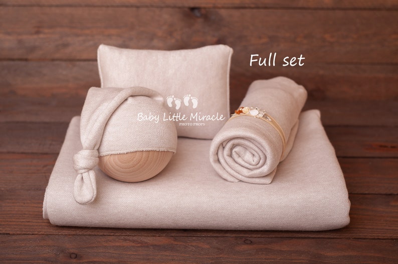 K&ouml;nnte beinhalten: Ein beiges Neugeborenen-Foto-Requisitenset. Das Set enth&auml;lt eine Decke, ein Kissen, eine M&uuml;tze mit Holzsockel und eine gerollte Wickelunterlage mit einem Blumenstirnband. Der Text "Baby Little Miracle Photo Props" ist auf der M&uuml;tze zu sehen. Die Worte "Full set" sind ebenfalls sichtbar.