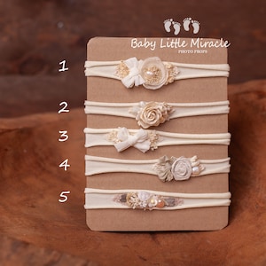 May include: Five white elastic headbands with different floral and pearl embellishments. The headbands are numbered 1 through 5 on a beige card with the text "Baby Little Miracle Photo Props".