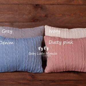 Puede incluir: Cuatro almohadas rectangulares de punto en gris, denim, marfil y rosa empolvado. Cada almohada presenta un dise&ntilde;o de punto trenzado. Las almohadas est&aacute;n dispuestas sobre una superficie de madera oscura. Los textos "Grey", "Denim", "Ivory" y "Dusty pink" est&aacute;n escritos en las almohadas.