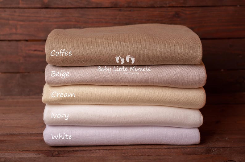 K&ouml;nnte beinhalten: Ein Stapel von sechs gefalteten Decken in den Farbt&ouml;nen Braun, Beige, Creme, Elfenbein und Wei&szlig;. Die oberste Decke ist mit "Coffee" beschriftet, die anderen mit "Beige", "Cream", "Ivory" und "White". Die Decken sind f&uuml;r Neugeborene.