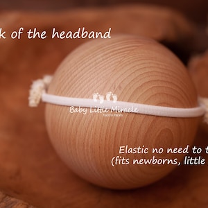 May include: White elastic headband with the text "Baby Little Miracle" on it. The headband is shown on a wooden surface. The text "Elastic no need to tie (fits newborns, little girls)" is also visible.