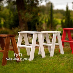 Könnte beinhalten: Vier kleine Holz-Trittleitern auf einer Wiese. Eine ist braun, zwei sind weiß und eine ist rot. Die Hocker haben ein A-Rahmen-Design. Der Text "Baby Little Miracle PHOTO PROPS" ist sichtbar.
