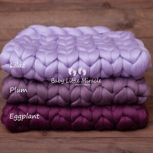 May include: Three chunky knit blankets in shades of lilac, plum, and eggplant. The blankets are stacked on top of each other and have a braided texture. The text "Baby Little Miracle Photo Props" is printed on the middle blanket.