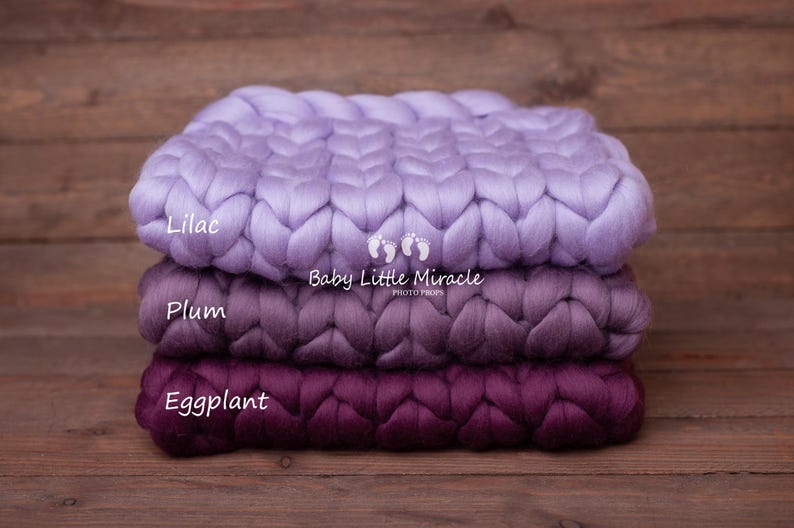 May include: Three chunky knit blankets in shades of lilac, plum, and eggplant. The blankets are stacked on top of each other and have a braided texture. The text "Baby Little Miracle Photo Props" is printed on the middle blanket.