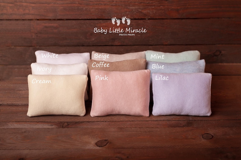 K&ouml;nnte beinhalten: Eine Auswahl an kleinen, rechteckigen Kissen in Pastellfarben: Wei&szlig;, Elfenbein, Creme, Rosa, Beige, Kaffee, Mint, Blau und Flieder. Die Kissen sind auf einer dunklen Holzoberfl&auml;che angeordnet, mit den Farbbezeichnungen.