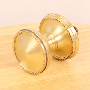 May include: A gold door knob with a rope design around the edge.